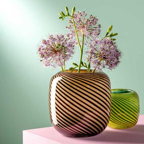 Vase FILO COLORI mit rosa Allium-Blüten auf rosa Podest, daneben grüne Vase