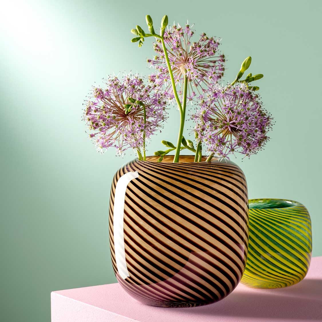 Vase FILO COLORI braun mit rosa Allium-Blüten und grüner Begleitvase auf Tisch