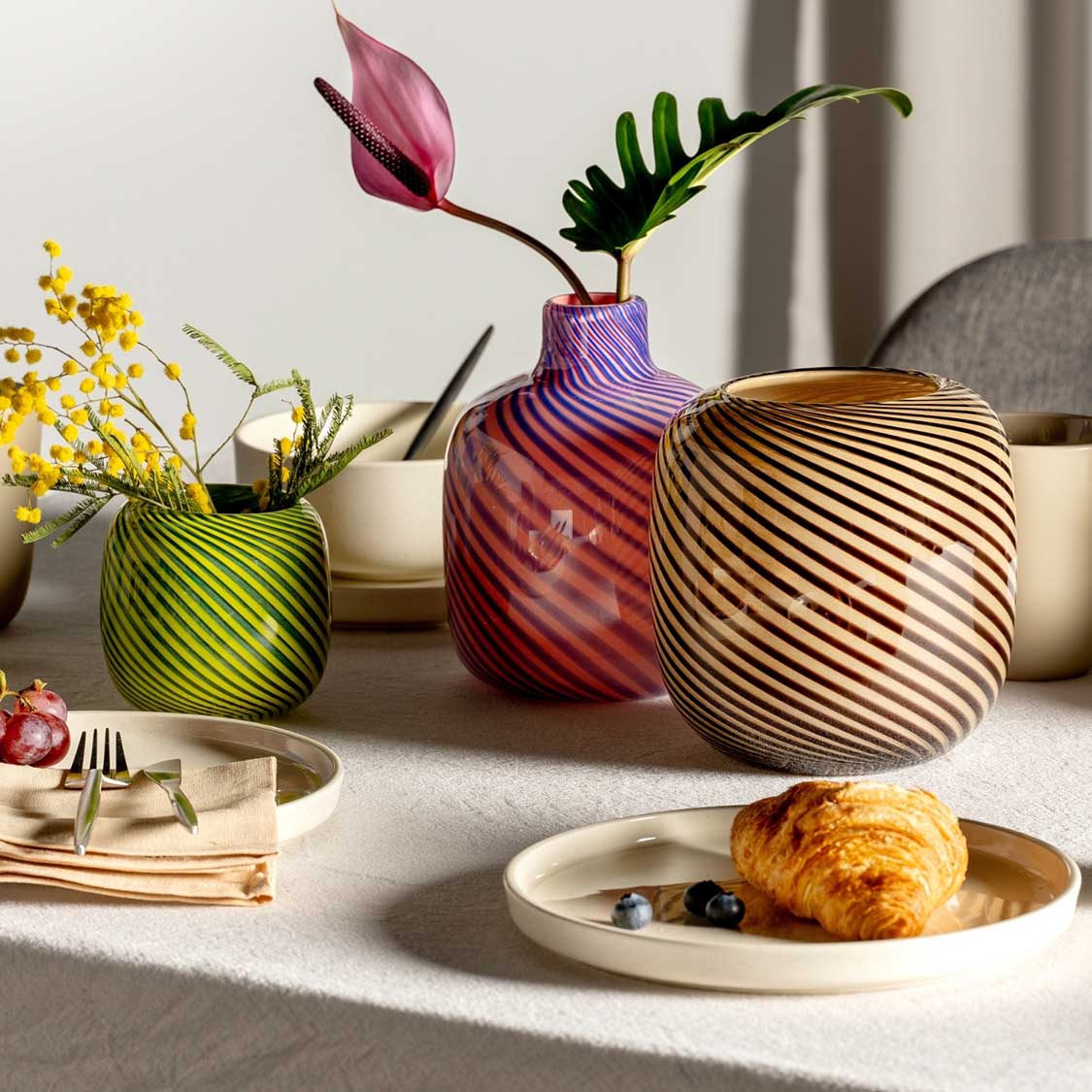 Vase FILO COLORI braun auf gedecktem Tisch mit Blumen und Croissant