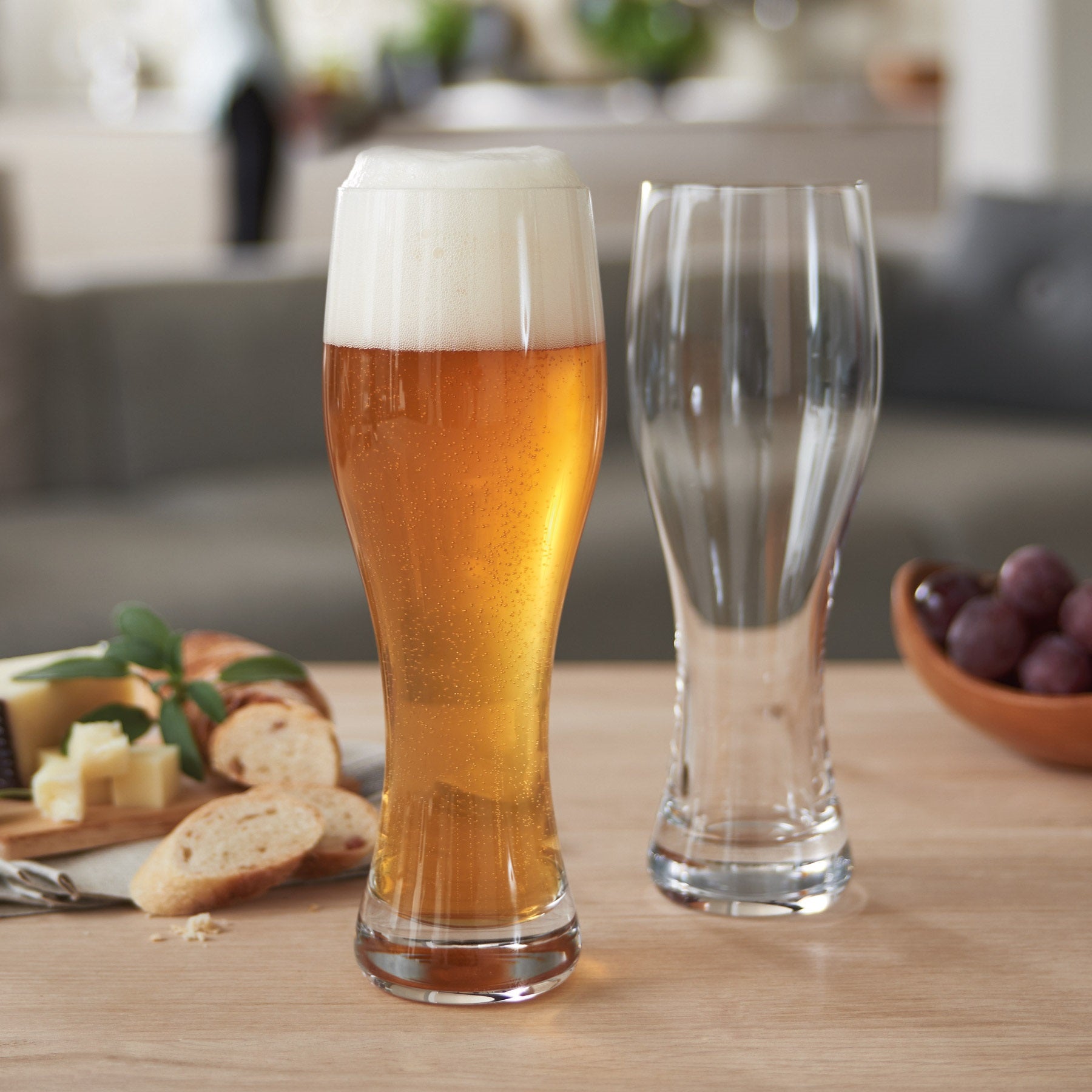 Weizenbierglas TAVERNA 500 ml 2er-Set, eines gefüllt mit Bier, auf Wohnzimmertisch mit Käse und Trauben