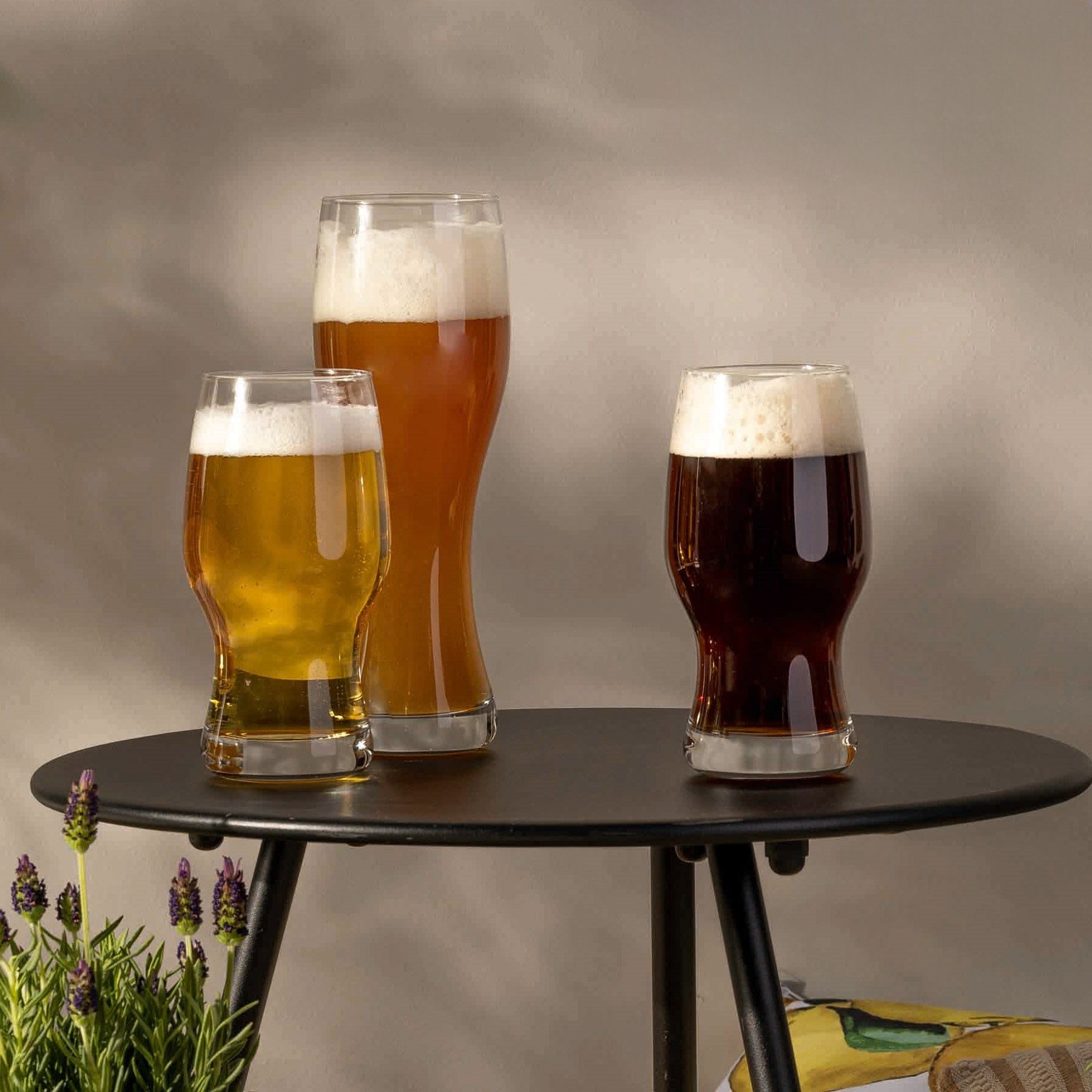 Drei Biergläser mit verschiedenen Bieren auf schwarzem Tisch, Lavendel daneben