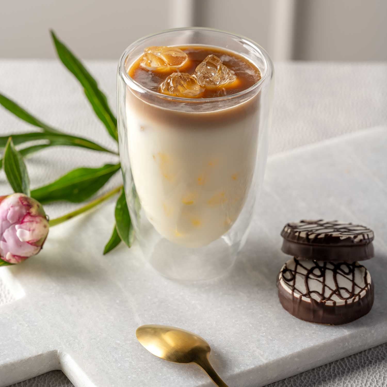 Doppelwandbecher DUO mit Eiskaffee auf Tablett, Blume und Schokolade