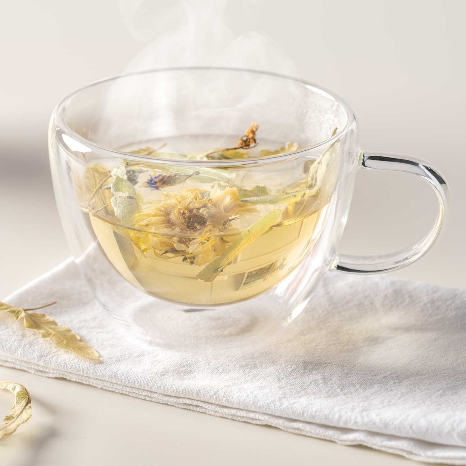 Teetasse DUO mit Kräutertee auf weißem Tuch, dampfend