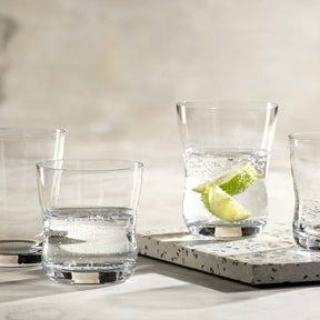 Trinkgläser VITA auf Betontablett, eines mit Limettenscheibe und Eiswürfeln