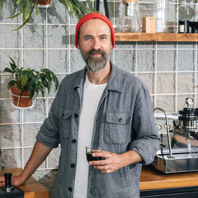 Mann mit rotem Beanie in Werkstatt hält Espressoglas GOCCE
