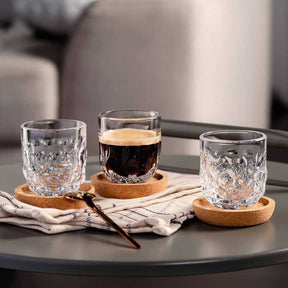 Espressoglas GOCCE auf Korkuntersetzern mit Getränken auf schwarzem Tisch