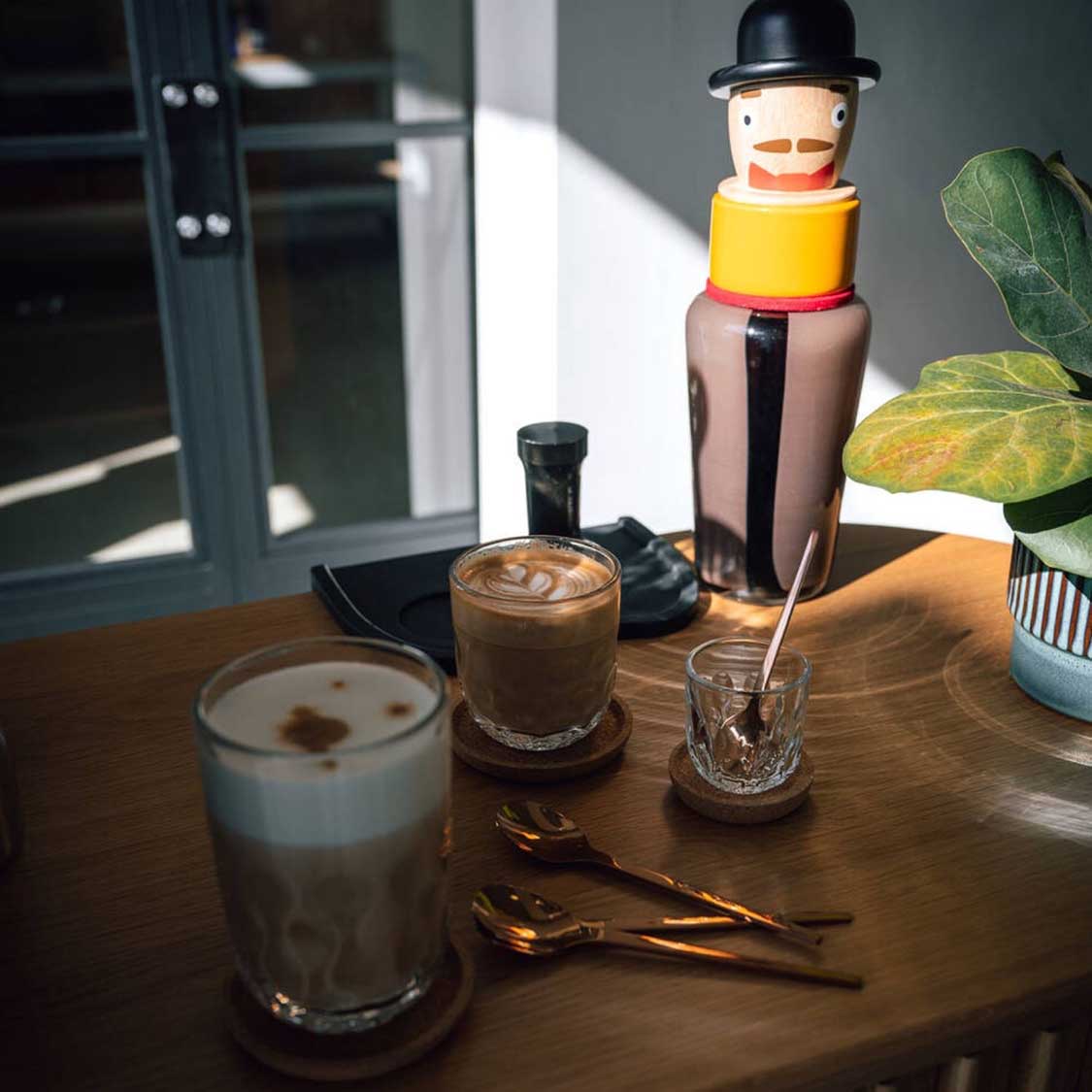 Espressogläser GOCCE auf Holztisch mit Kaffeegetränken und Dekoration