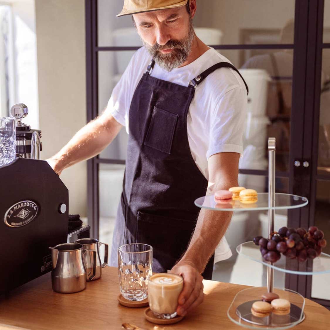 Mann in Schürze bereitet Kaffee mit Kaffeeglas GOCCE zu