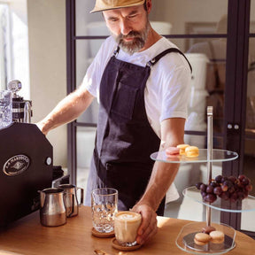 Mann in Schürze bereitet Kaffee mit Kaffeeglas GOCCE zu