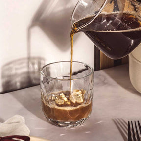 Kaffeeglas GOCCE wird mit Kaffee gefüllt, Tisch mit Besteck und Serviette