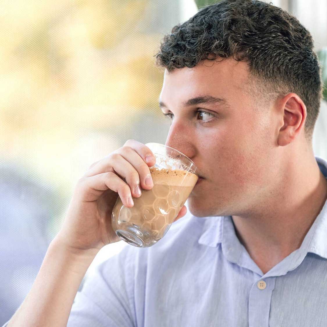 Mann trinkt aus Latte Macchiato Glas GOCCE mit Getränk