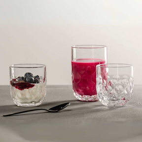 Latte Macchiato Gläser GOCCE mit Joghurt, Beeren und Saft auf grauer Oberfläche mit Löffel
