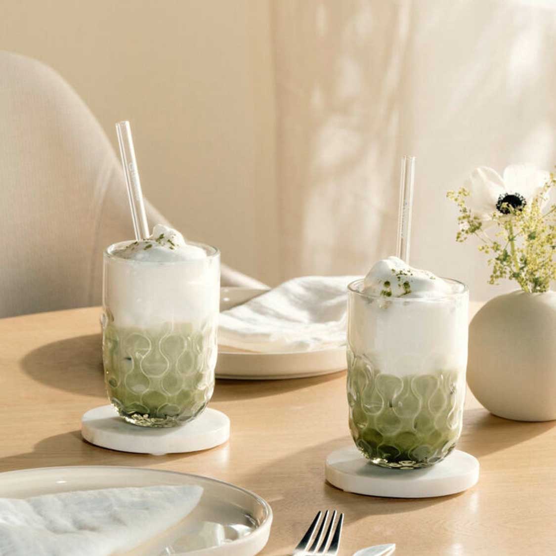 Zwei Latte Macchiato Gläser GOCCE mit Strohhalmen auf gedecktem Tisch