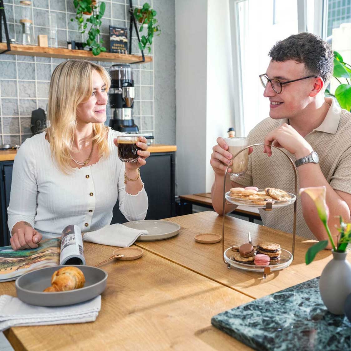 Paar beim Kaffeetrinken am Holztisch mit Latte Macchiato Gläsern