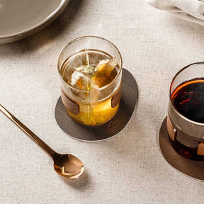 Becher NOVO LEGNO mit Getränk auf Untersetzer, Tisch mit Besteck