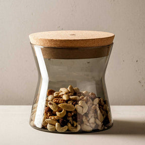Dose FORMA X mit Kordeckel, gefüllt mit Cashewkernen, auf weißem Untergrund