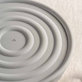Silikondeckel CUCINA grau von oben, konzentrische Rillen und Wolkensymbol in der Mitte