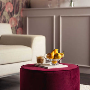 Glasvase auf burgunderfarbenem Pouf in Wohnzimmer mit Obst und Getränk