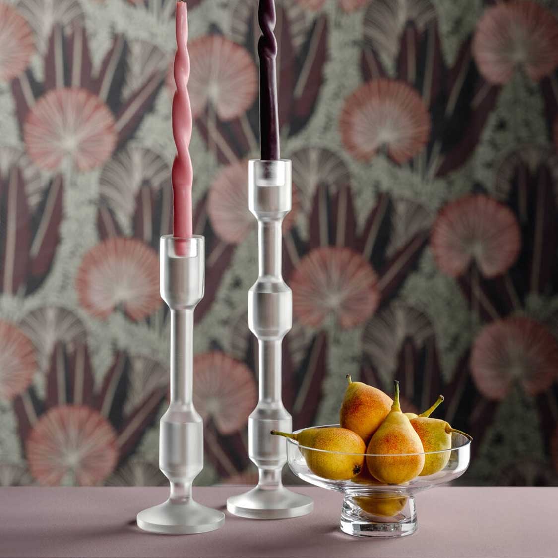 Zwei Glasleuchter RIALTO mit Kerzen und Obstschale auf Tisch vor Blumentapete