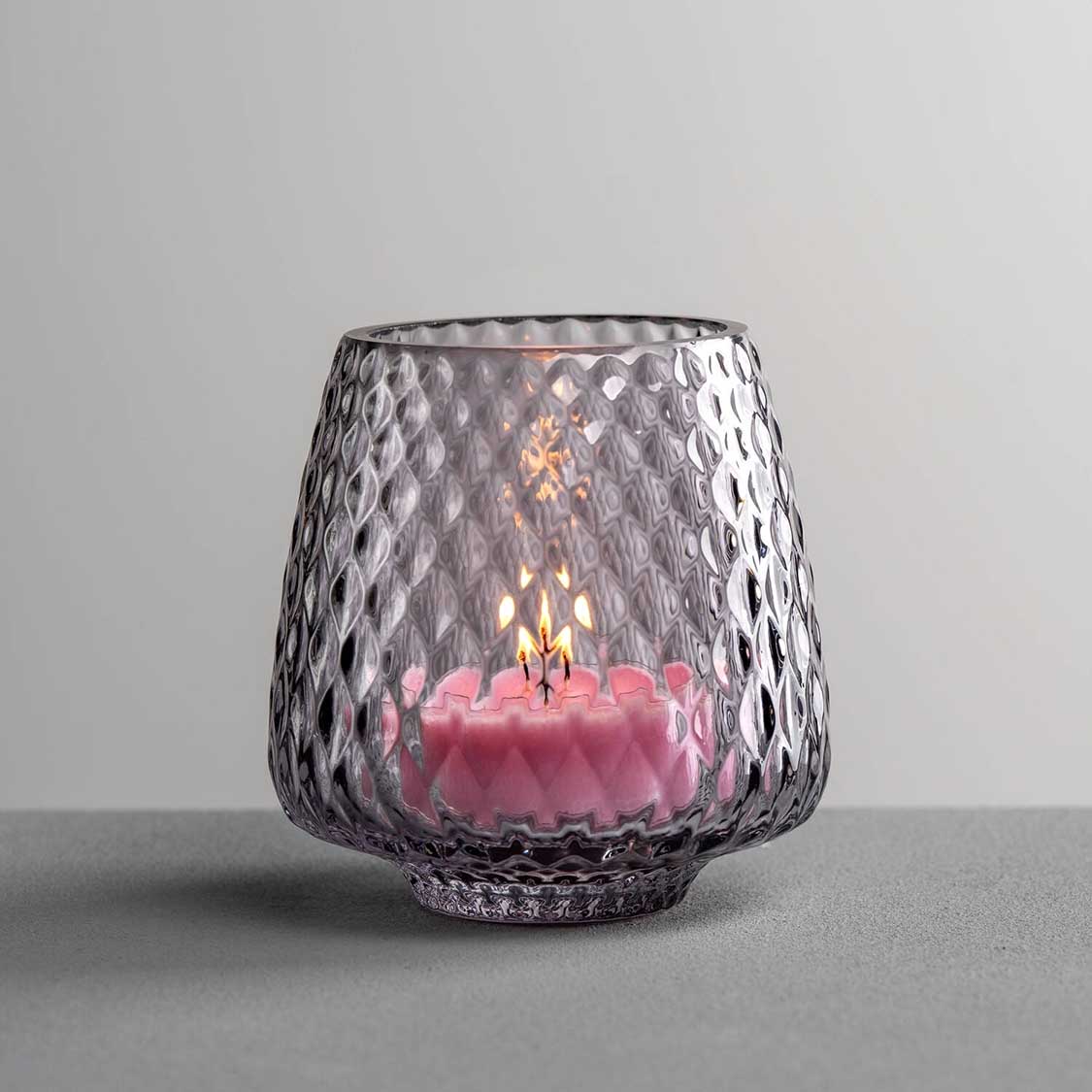 Tischlicht GIULIA grau mit brennender rosa Kerze auf grauem Untergrund