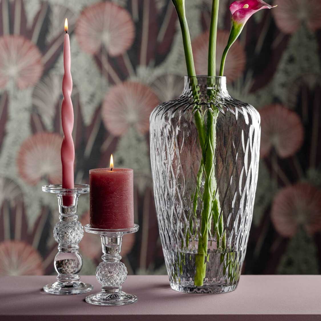 Vase GIULIA mit Blumen, Kerzen und Kerzenhaltern auf Tisch vor gemustertem Hintergrund