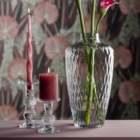 Vase GIULIA mit Blumen, Kerzen und Kerzenhaltern auf Tisch vor gemustertem Hintergrund
