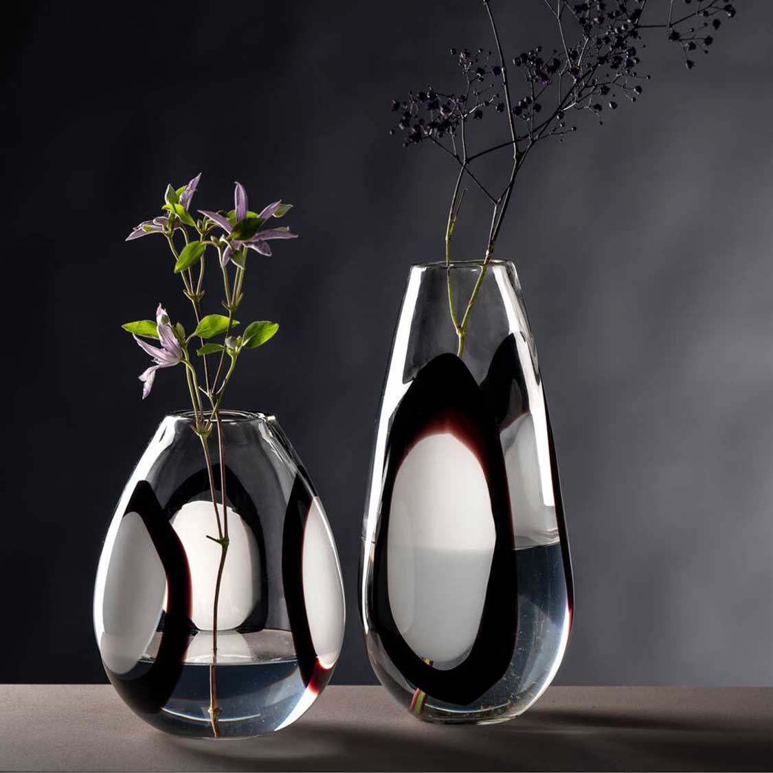 Zwei Glasvasen OCCHI BIANCHI mit weißem Oval-Muster, eine mit Blüten, eine mit Zweigen gefüllt