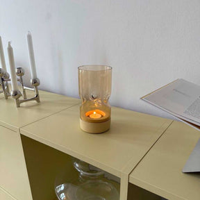 Tischlicht SOLE auf Schreibtisch mit brennender Kerze, Kerzenhalter und Buch im Hintergrund