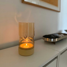 Tischlicht auf Sockel SOLE auf weißem Sideboard in Wohnraum, brennende Kerze sichtbar