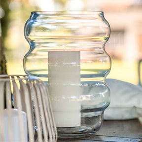 Windlicht SOLE mit brennender Kerze auf Gartentisch im Freien