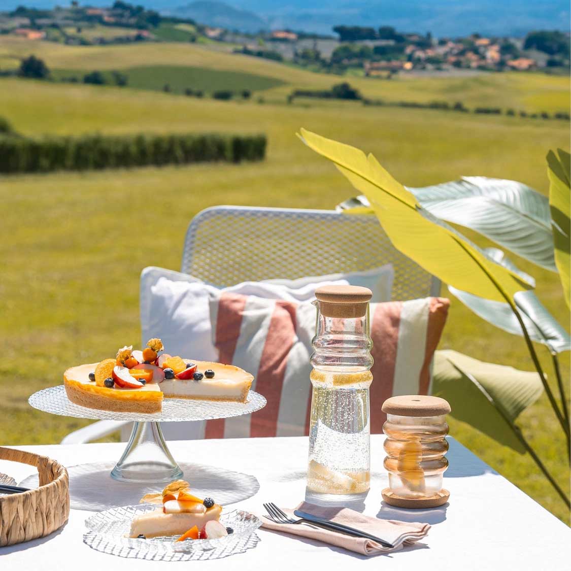 Karaffe SOLE mit Wasser auf gedecktem Gartentisch, Landschaftsblick