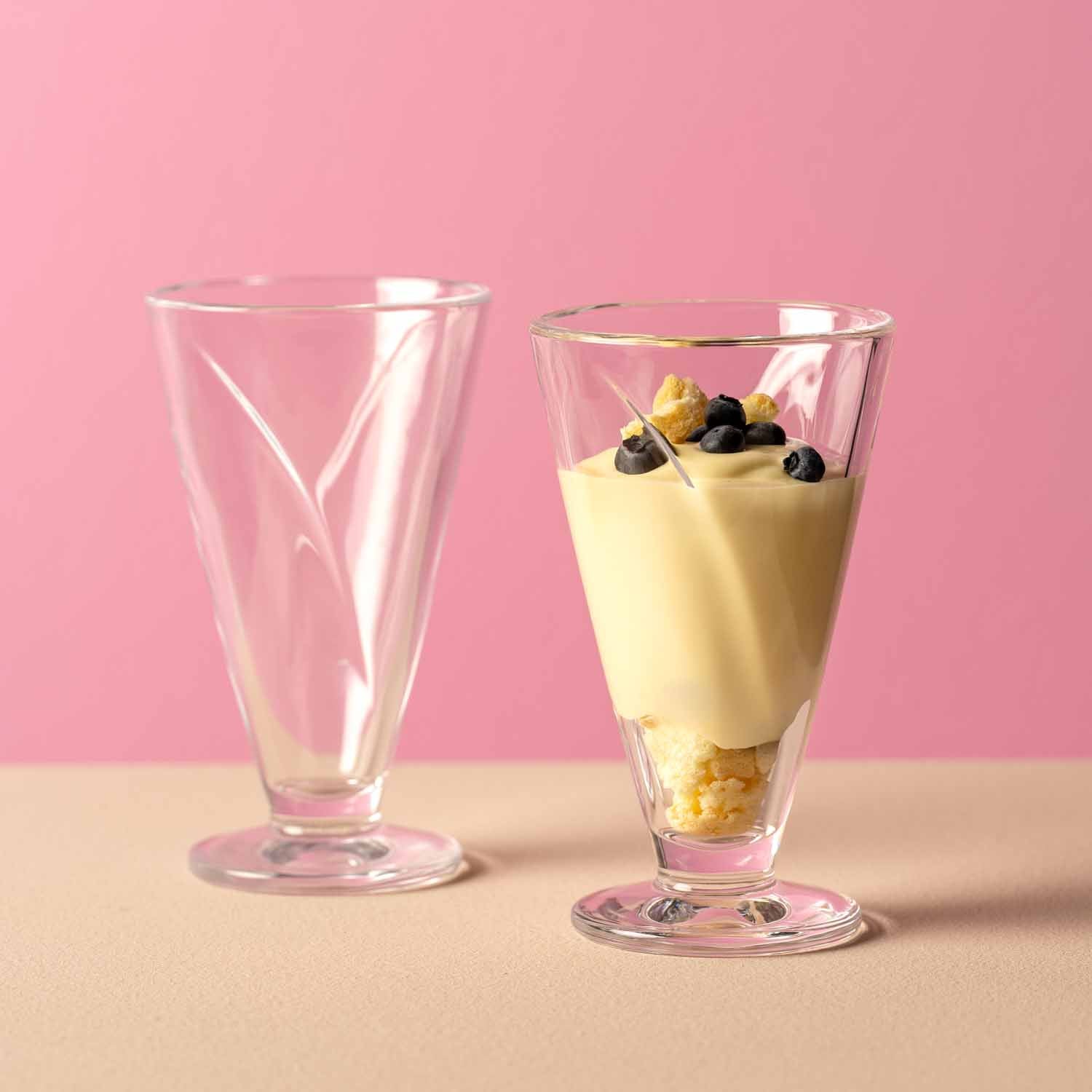Zwei Eisbecher CONO aus Glas, einer leer, einer mit Dessert und Beeren gefüllt