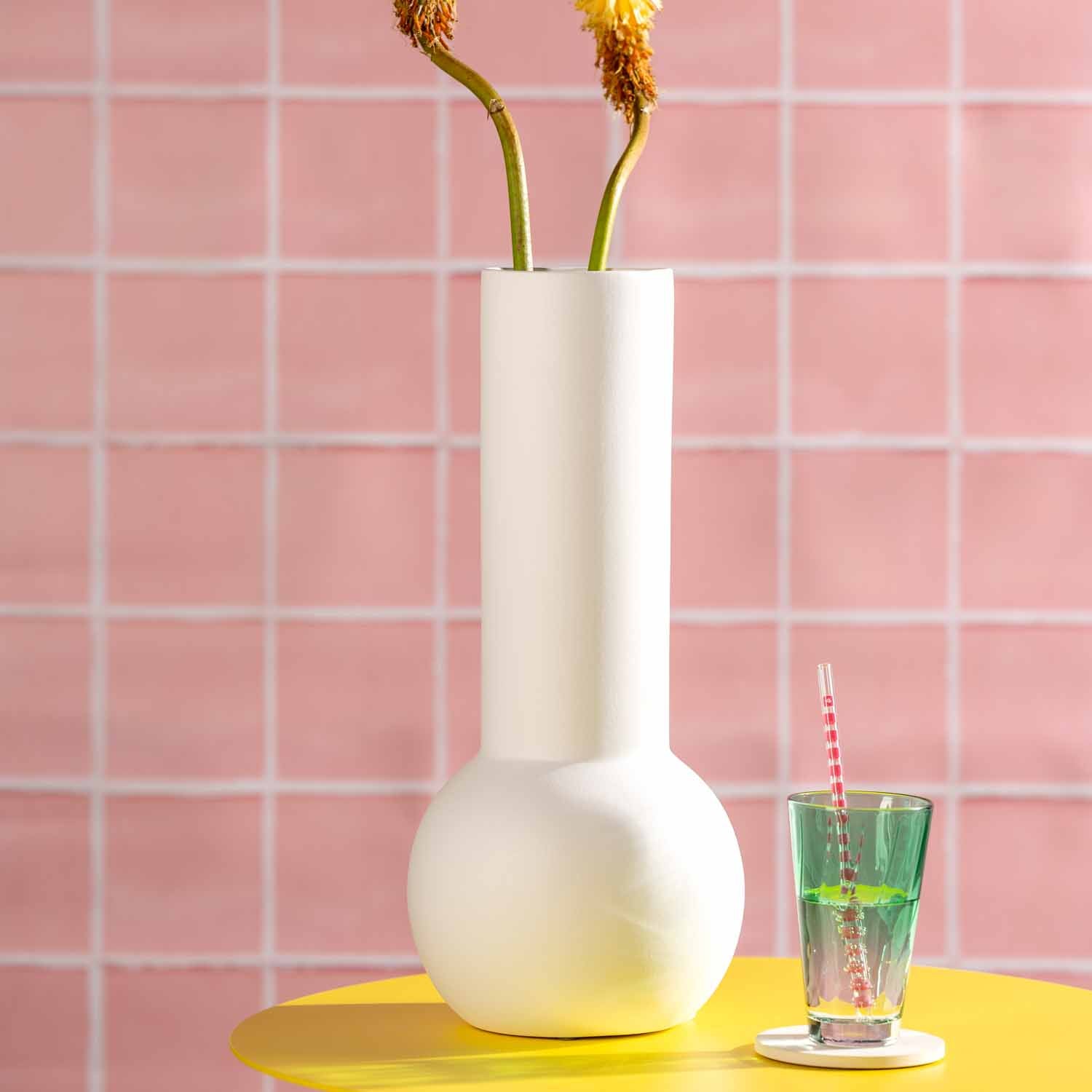 Keramikvase BRERA mit getrockneten Blüten auf gelbem Tisch vor rosa Fliesenwand