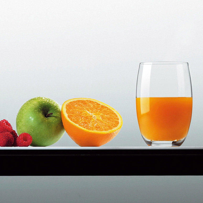 Trinkglas CHEERS mit Orangensaft, daneben Obst und Beeren