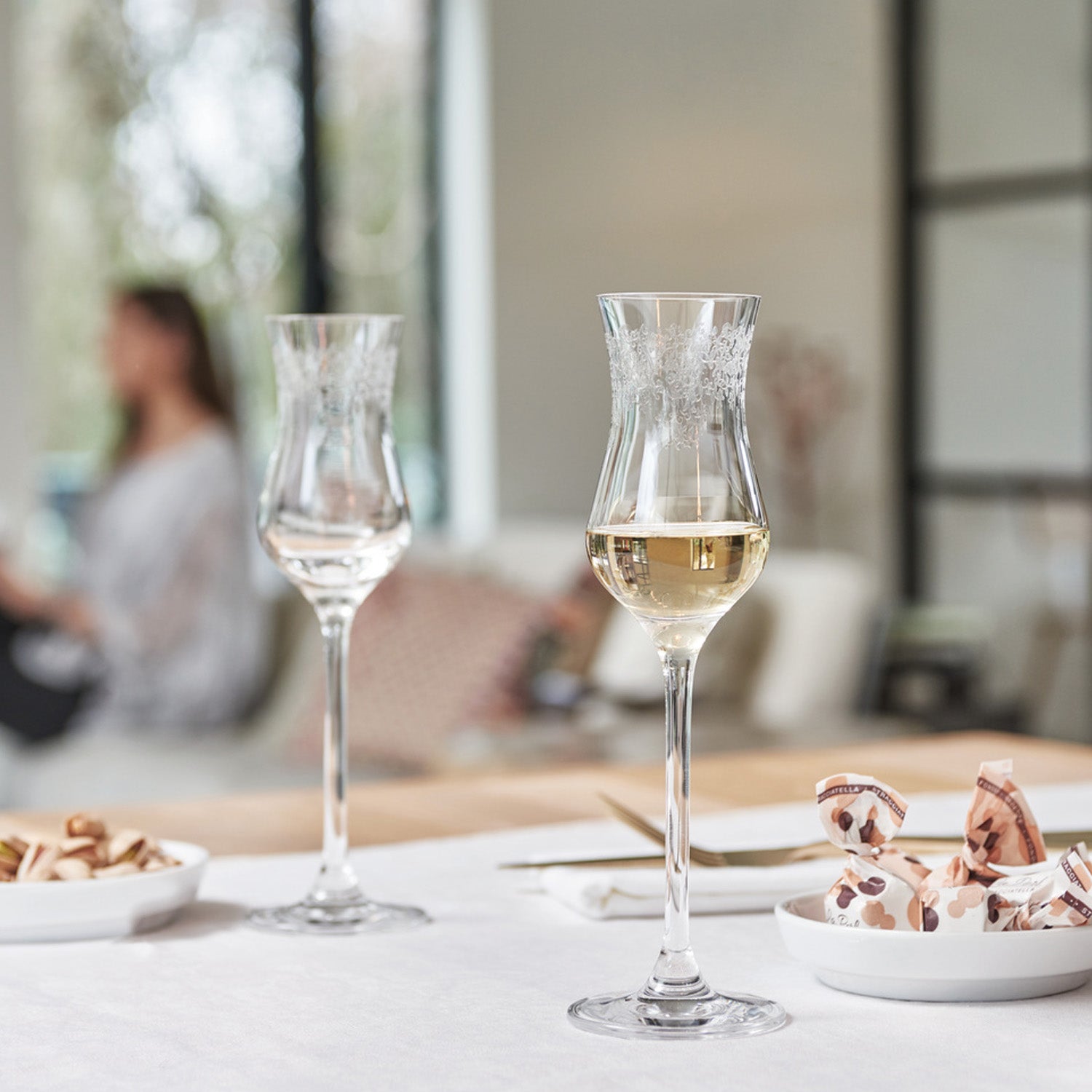 Zwei Grappagläser CHATEAU auf gedecktem Tisch mit Appetizern und unscharfem Hintergrund