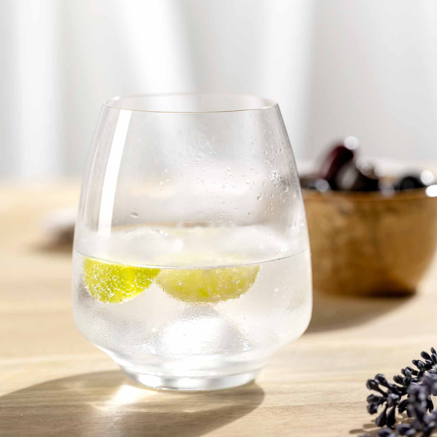 Trinkglas CESTI mit Eiswürfeln und Limettenscheiben auf Holztisch