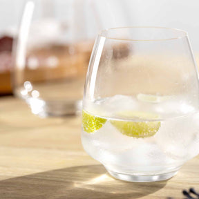 Trinkglas CESTI mit Eiswürfeln und Limettenscheiben auf Holztisch