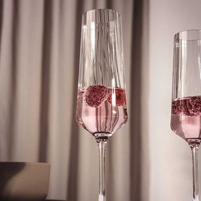 Sektglas PAOLO mit Roséwein und Eiswürfeln gefüllt, neben zweitem Glas vor Vorhang
