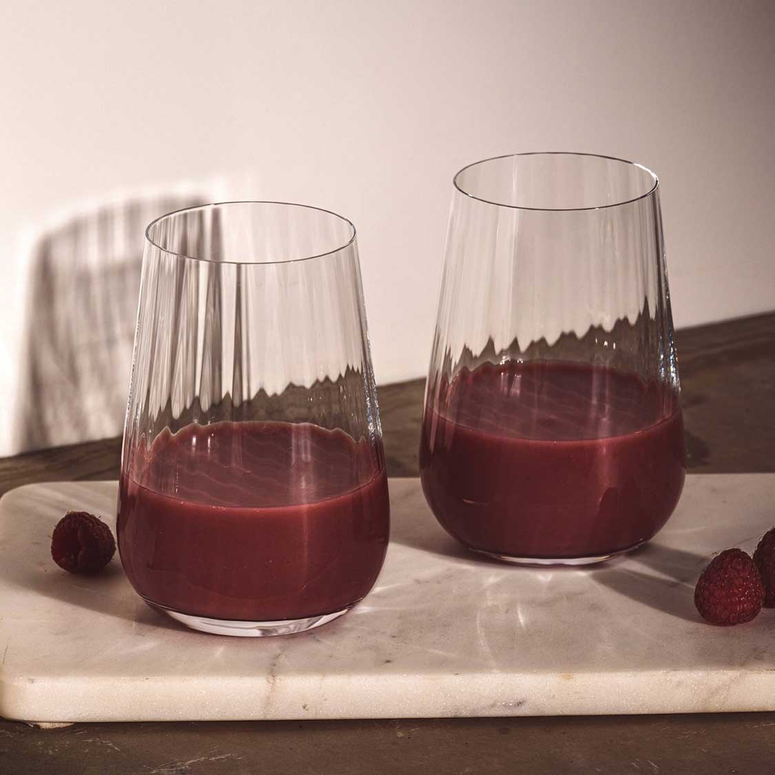 Trinkglas PAOLO mit rotem Saft auf Marmorplatte, daneben Beeren