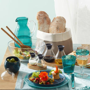 Gedeckter Tisch mit Glas-Schale, Brot, Besteck und Getränken