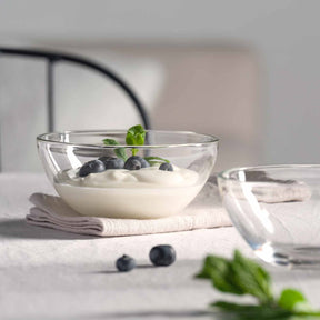 Glasschale mit Joghurt und Blaubeeren auf hellem Untergrund
