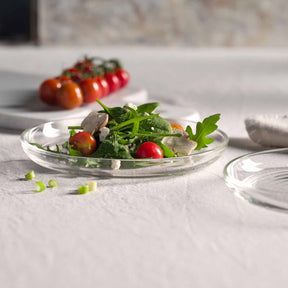 Glasteller mit Salat und Gemüse auf gedecktem Tisch