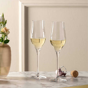 Zwei gefüllte Champagnergläser BRUNELLI auf Marmortisch mit Blumenvase