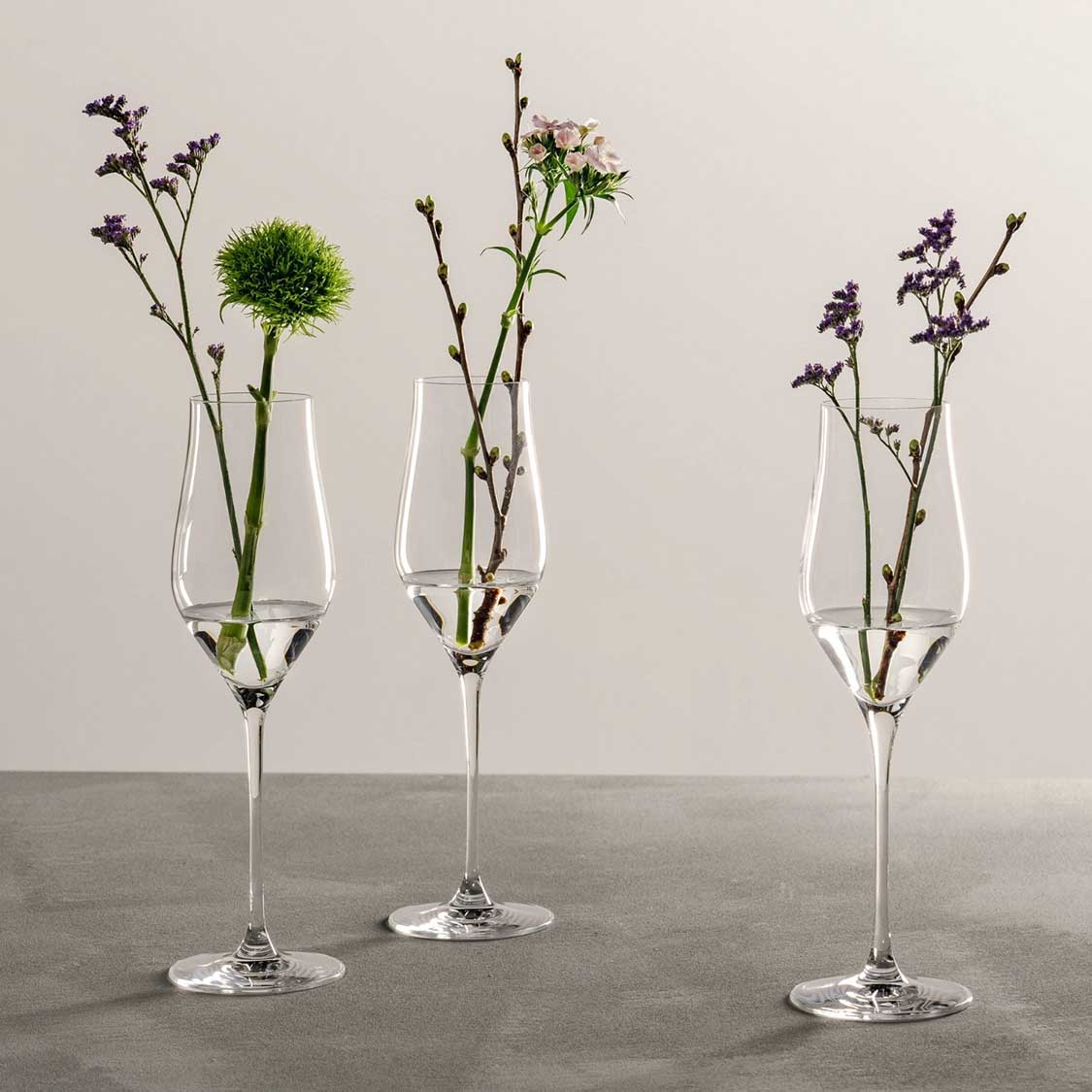 Drei Champagnergläser BRUNELLI mit Wildblumen gefüllt auf grauem Untergrund