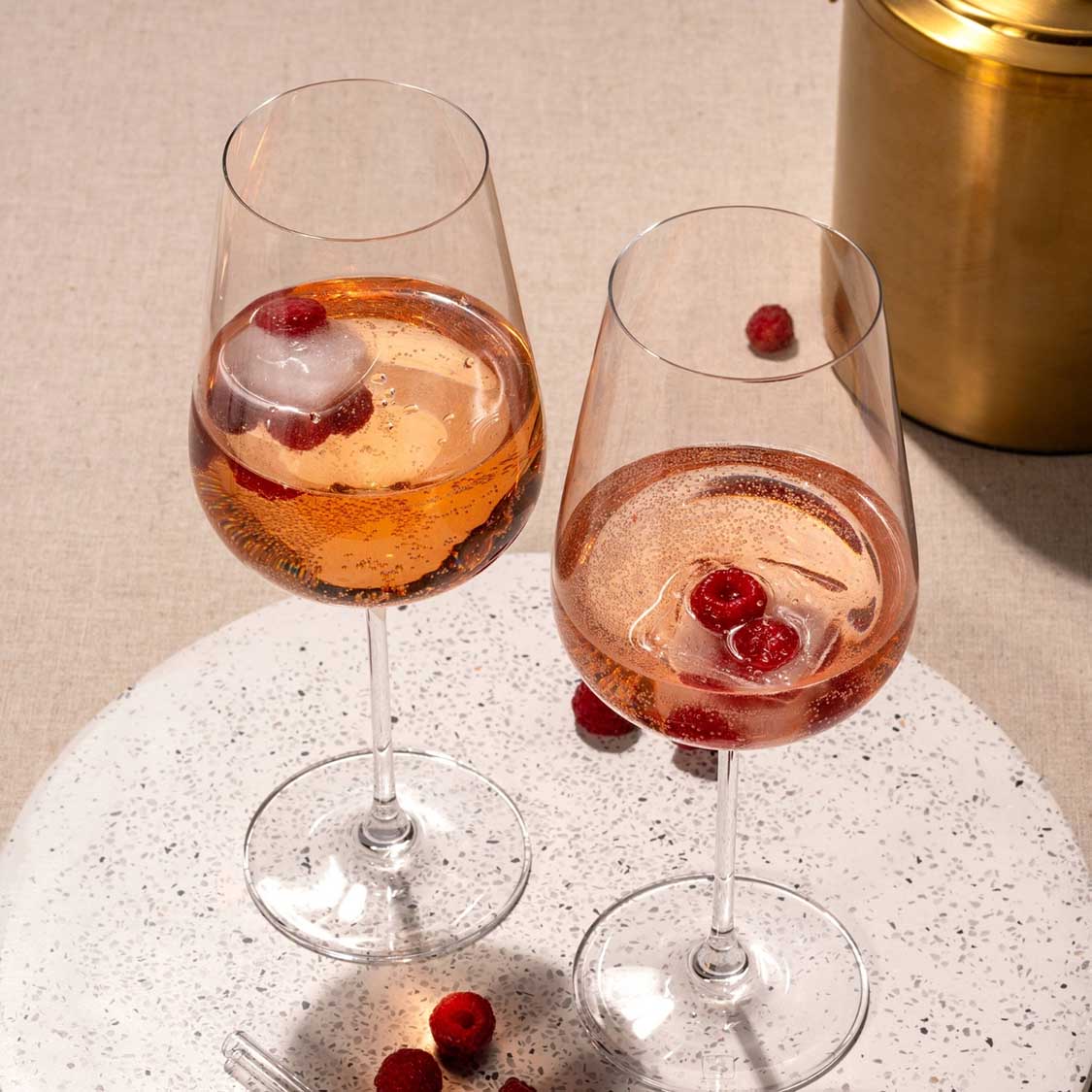 Zwei Weißweingläser BRUNELLI mit Roséwein und Eiswürfeln auf weißem Tisch