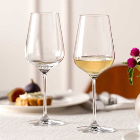 Zwei Weißweingläser BRUNELLI auf gedecktem Tisch mit Blumen und Speisen