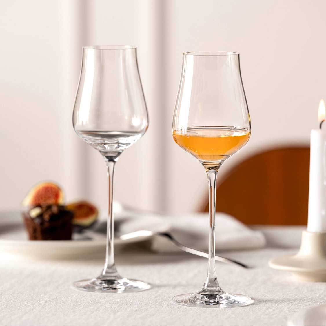 Grappaglas BRUNELLI, eines gefüllt mit Spirituose, auf gedecktem Tisch mit Obst