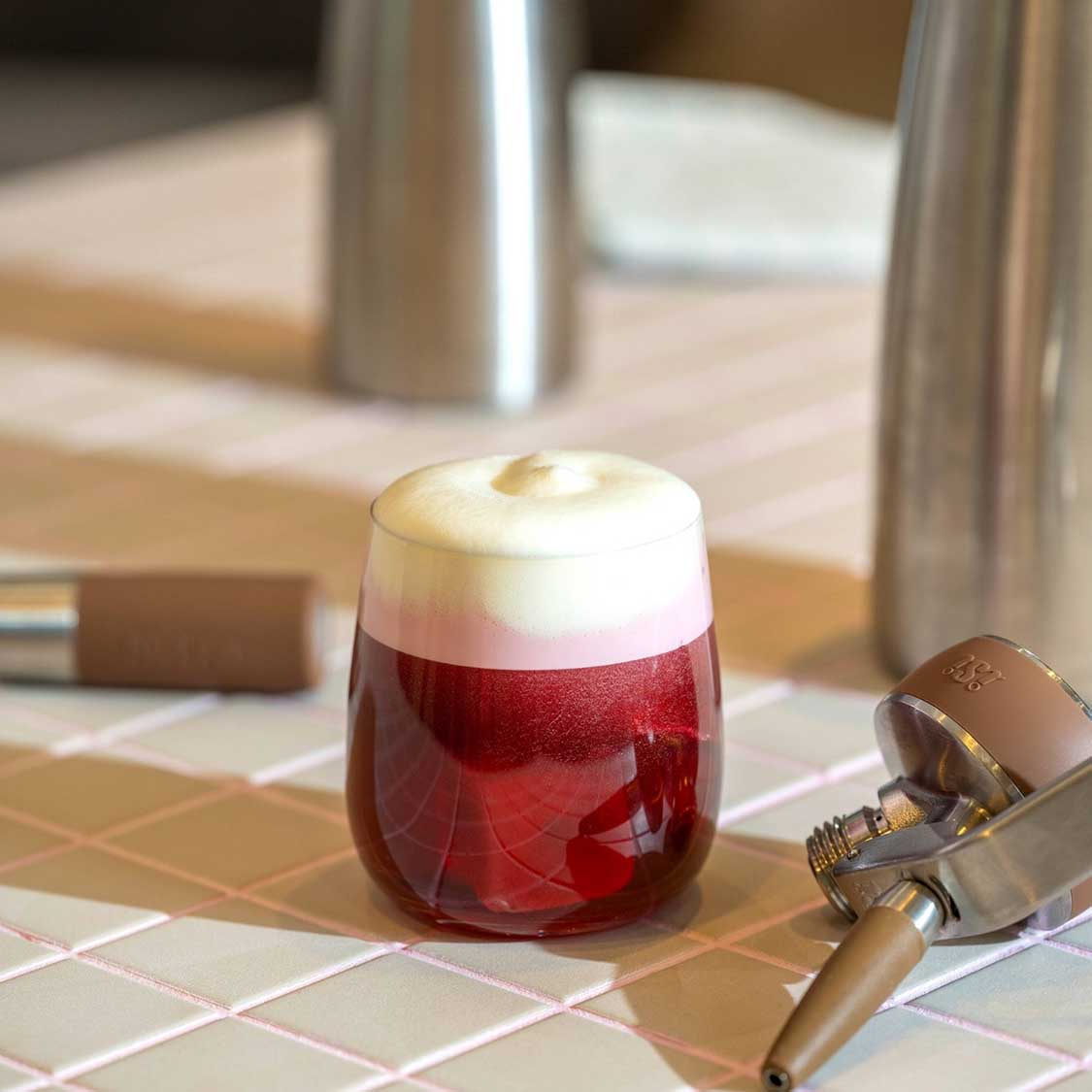 Trinkglas BRUNELLI mit rotem Getränk und Schaumkrone auf Holztisch