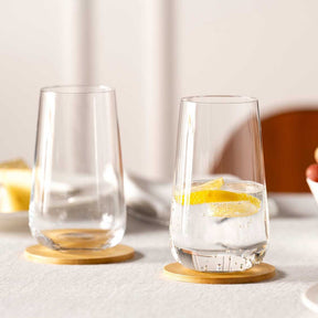 Zwei Trinkgläser BRUNELLI mit Zitronenscheibe und Wasser auf Holzuntersetzern
