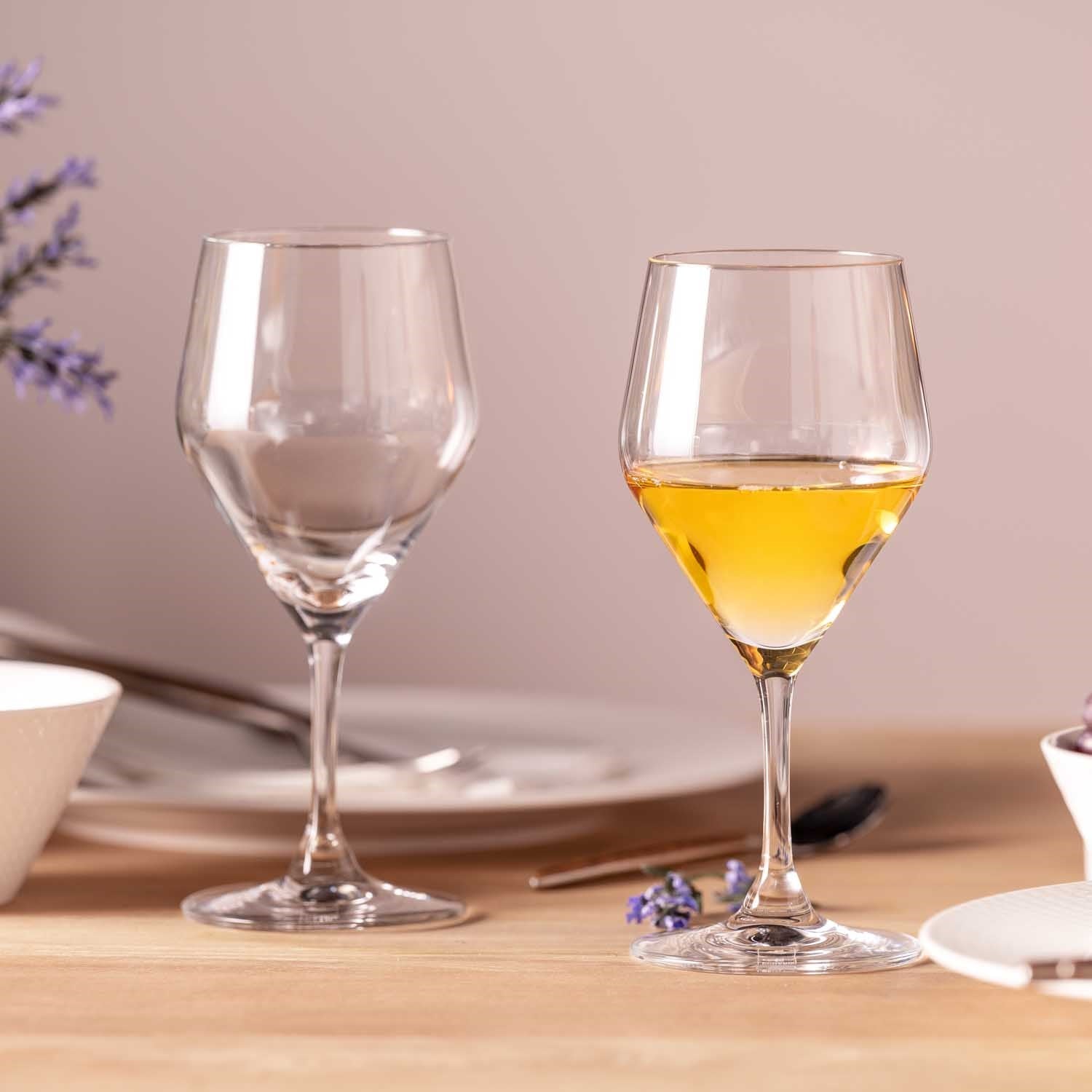 Zwei Weißweingläser TWENTY 4 auf gedecktem Tisch, eines leer, eines mit gelblichem Wein gefüllt